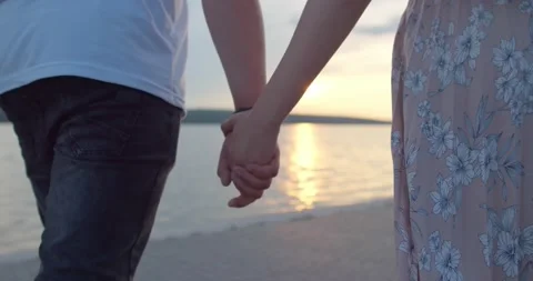 Lovers hold hands during a walk by the lake Stock Footage 135264789