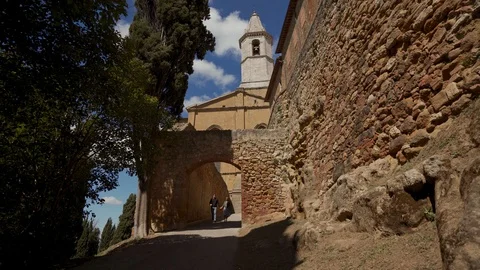 Lovers holding hands go through ancient gate of fortress of Pienza, Tuscany 库存影片 123871834