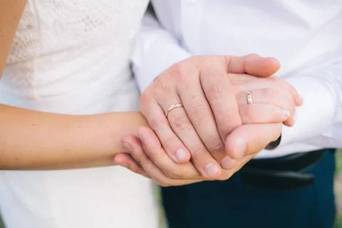 Lovers holding hands with gold wedding rings Stock Photos