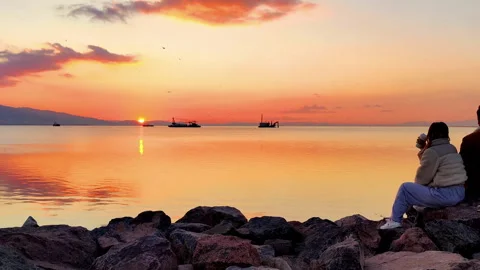 Lovers Sitting on the Beach Cliffs Drinking Coffee at Red Sunset Stock Footage 252099578