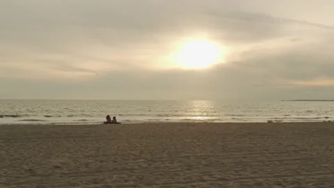 Lovers take in a gorgeous Pacific Ocean sunset on a sandy beach Stock Footage 133849688
