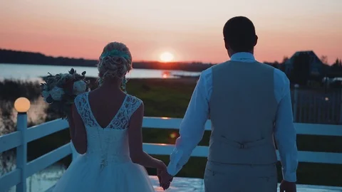 Lovers walk down the pier into the sunset and gentle kiss. Cool footage Stock Footage 113996788