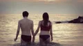 lovers walking into the sea at sunset holding hands and kissing each other HD Footage