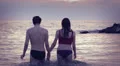 lovers walking into the sea at sunset holding hands and kissing each other HD Footage