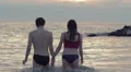 lovers walking into the sea at sunset holding hands and kissing each other HD Footage