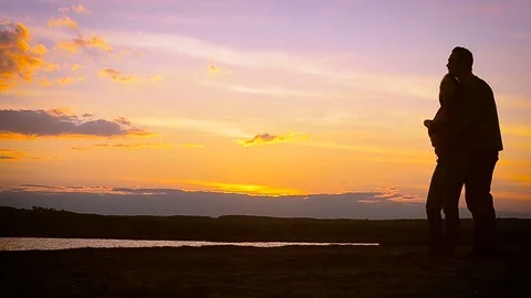 Lovers woman and man walking in sunset hand in hand, silhouettes of people at Stock Footage