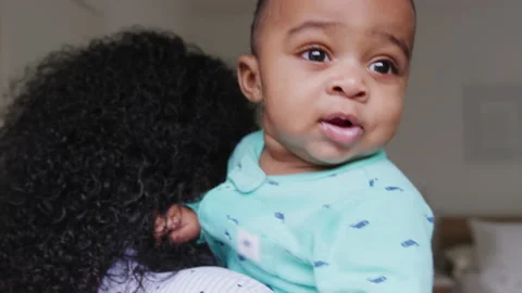 Loving African American Mother Wearing Pyjamas Cuddling Baby Son In Bedroom At Stock Footage