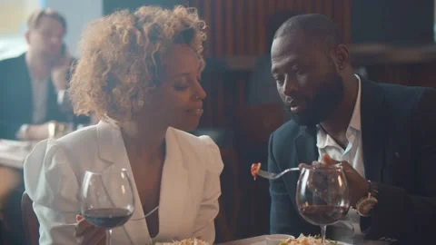 Loving black couple having dinner date feeding each other sitting in restaurant. Stock Footage