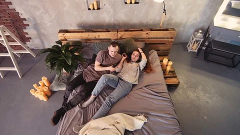 A loving couple on a bed smokes electronic cigarettes. Stock Footage 103160874