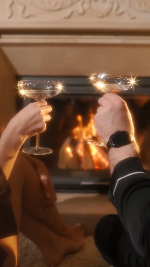 A loving couple on a date drinking an alcoholic cocktail near a fireplace Vidéo 333824319