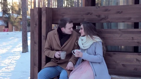 Loving couple drinking hot tea in backyard of cottage in winter Stock Footage 72318857
