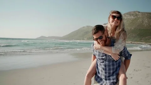 Loving couple having fun on beach piggy-back ride Stock Footage 83359547