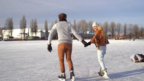 Loving couple having fun on ice in typical dutch landscape with windmill. Woman Stock Footage 225642257