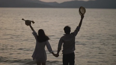 Loving couple holding hands while walking at sunset Stock Footage 100933815