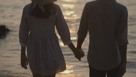 Loving couple holding hands while walking at sunset Stock Footage 100937969