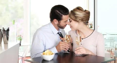 Loving couple kissing sitting at a table with wine glasses Stock Photos
