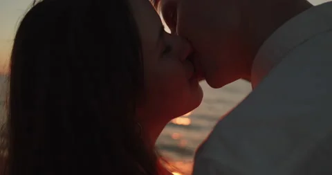 Loving couple make heart shape with hands in the sunlight at sunset on the beach Stock Footage 220730322