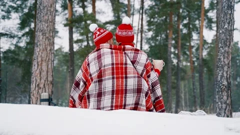 A loving couple in a pine forest sit on a fallen tree and drink hot tea. Stock Footage 146203670