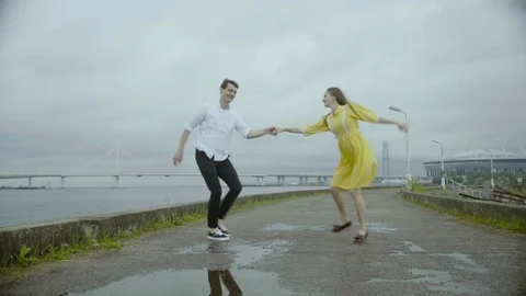 The loving couple on the river bank dancing together. Woman in nice yellow dress Stock Footage 80252293
