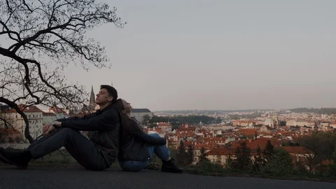 Loving couple sit back to back on observation deck with panoramic views of 库存影片 115291713