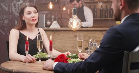 Loving couple sits at a table in a restaurant and drink champagne Stock Footage 105059779