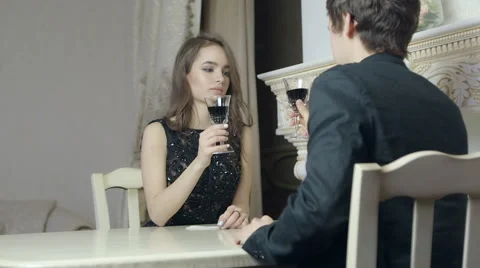 Loving couple sitting in front of each other, clink glasses with red wine. Stock Footage 61081808