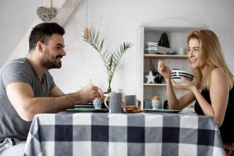 Loving couple sitting at a kitchen table, having a breakfast together Stock Photos