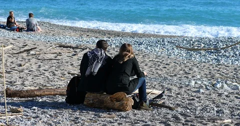 Loving Couple Sitting On A Tree Trunk On The Beach Stock Footage 122924000