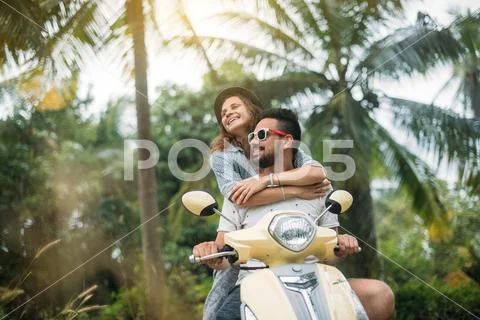A loving couple travels by scooter through the jungle in Southeast Asia. Stock Photos