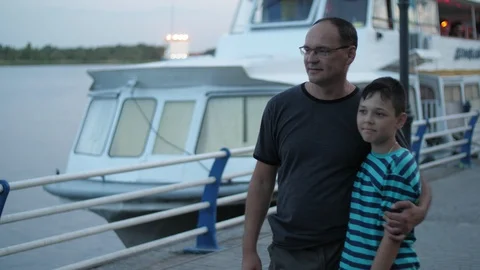 Loving daddy points with a finger on the cool yachts in the river to his young Vidéo 113484062