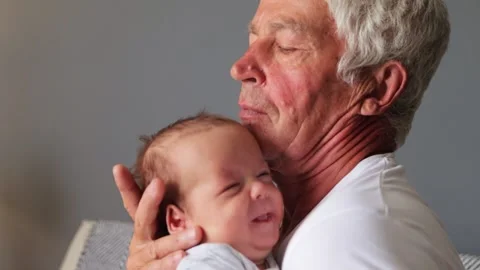Loving gray haired grandfather lovingly holding his newborn grandson senior 動画素材 291306055