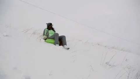 Loving guy and girl skate in the winter with a snowy mountain on snowtube Stock Footage