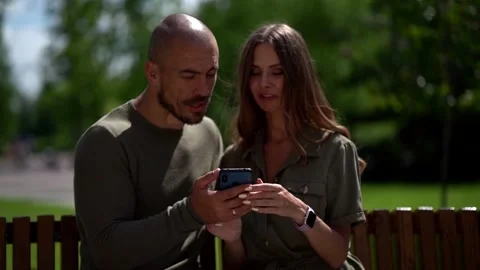 A loving, harmonious couple sit on a bench near a wooden fence: a bald middle 库存影片 134941790