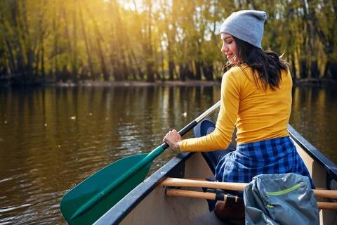 Loving her lakeside getaway. a young woman going for a canoe ride on the lake. Stock Photos