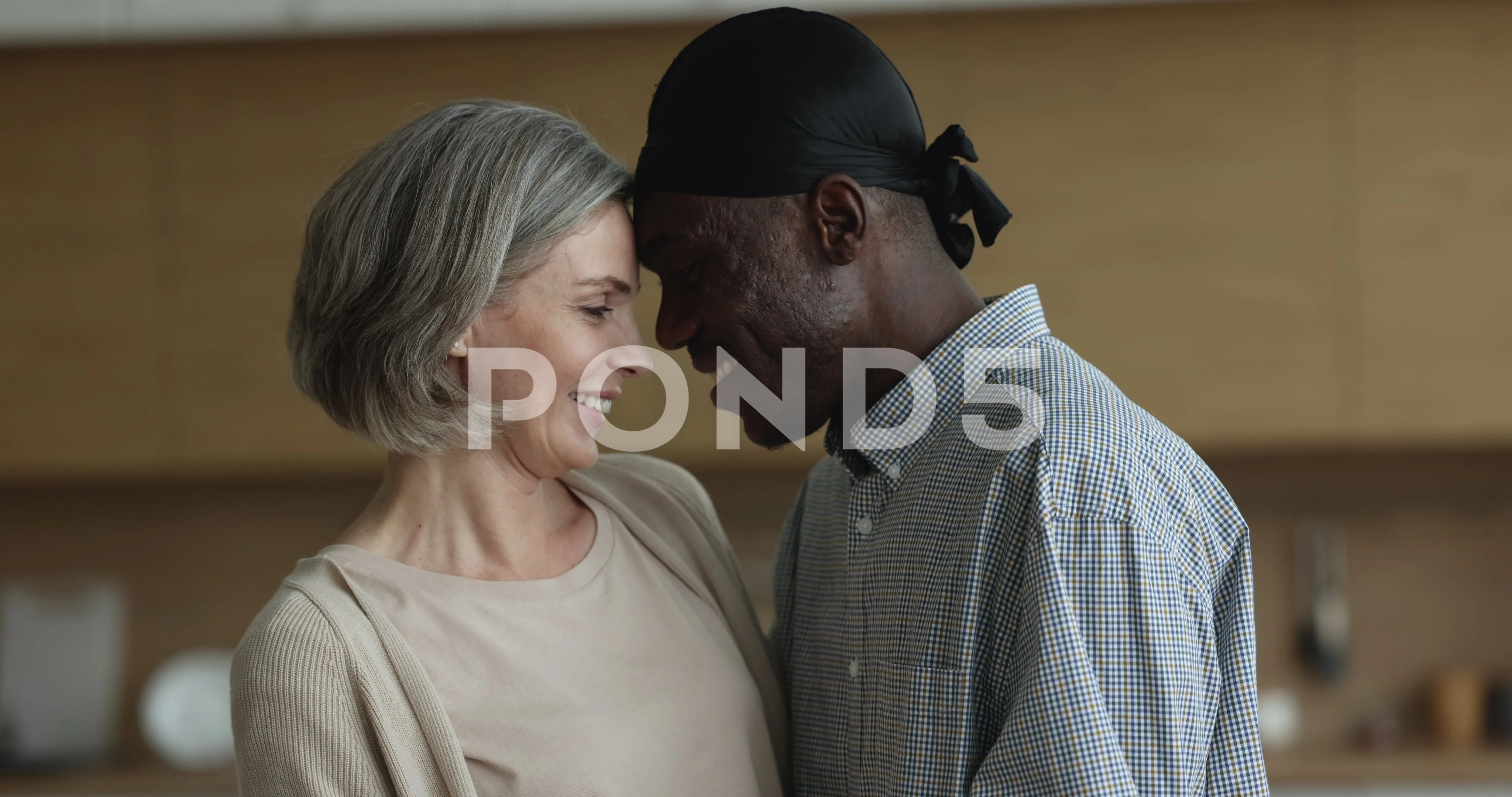 Loving mature multiethnic flirting couple pose in kitchen