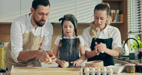 Loving mom with father teaching curious kid daughter learning kneading dough Stockbeeldmateriaal 218635448