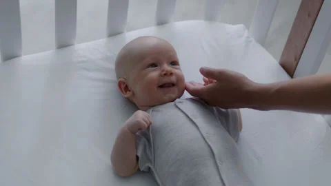 Loving mother gently stroking head of her smiling newborn baby lying in bed Stock Footage 305978801