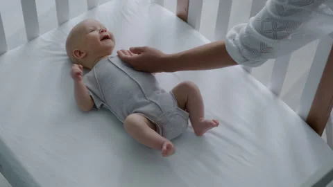 Loving mother gently stroking the head of her newborn baby lying in bed Stock Footage 305981984