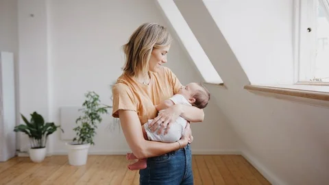 Loving Mother Holding Sleeping Newborn Baby At Home In Loft Apartment Stock Footage