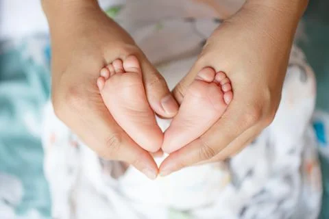 A loving parent holds their babys tiny feet, creating heart shape with their  Stock Photos