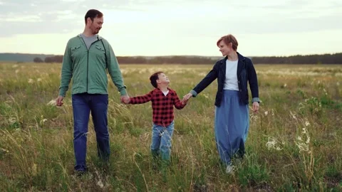 Loving parents hold son hands in field with growing plants in cloudy weather Stock Footage 257481371