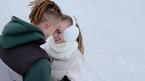 Loving partners hugging, laughing while standing on frozen lake surface, wearing Stock Photos