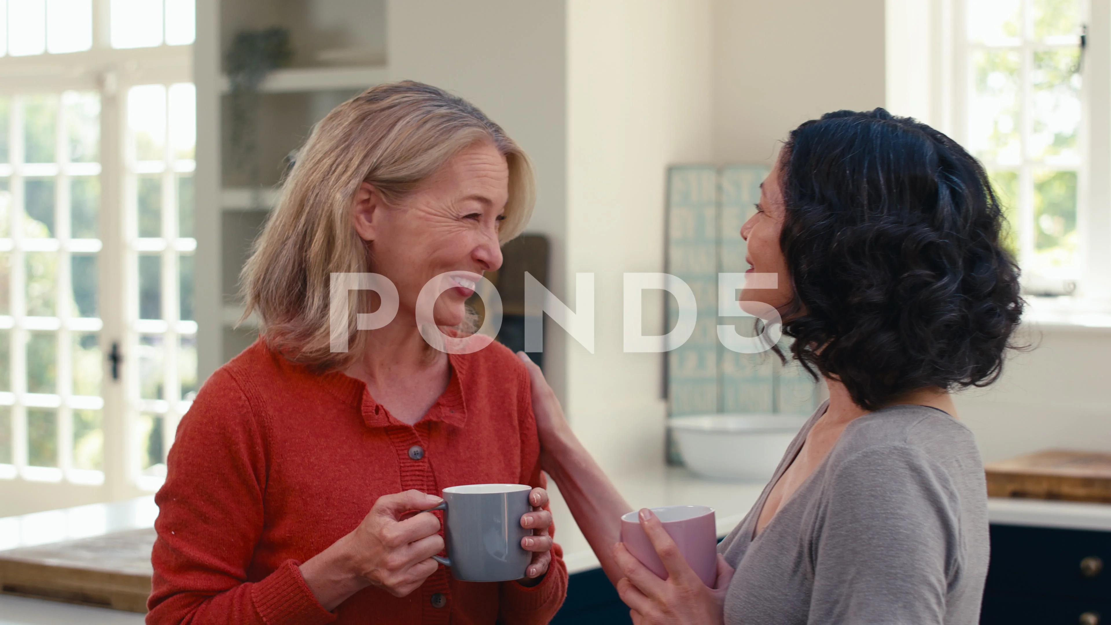 Loving Same Sex Mature Female Couple Drinking Coffee And Hugging In Kitchen