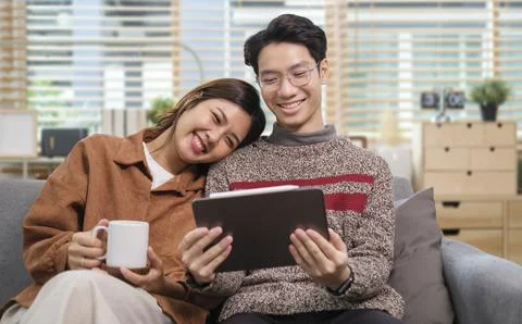 Loving young couple using digital tablet, watching movie together, enjoying.. Stock Photos