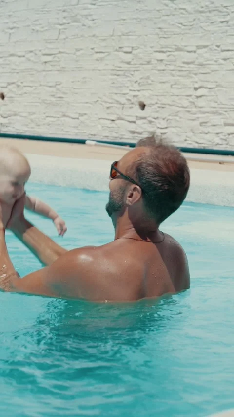 Loving young father wearing sunglasses joyfully lifting his cute baby boy out of Stock Footage 339278053