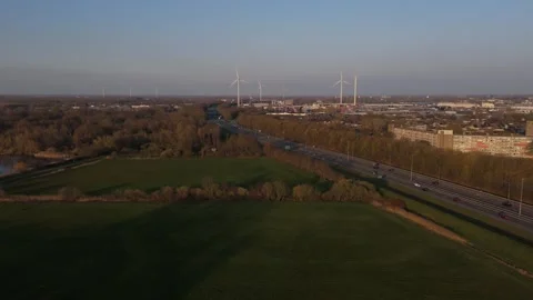 Low aerial approach over highway to wind turbines in warm evening light Stock Footage 335651612