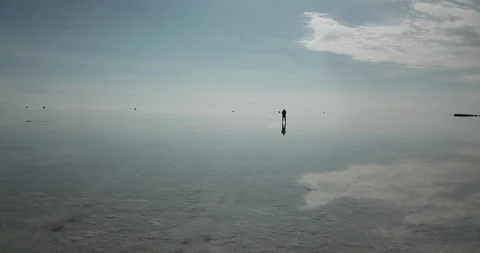 Low aerial circles quickly around a silhouetted figure in the Salar de Uyuni Vídeos de archivo 87491637