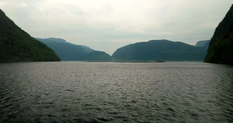 Low aerial dolly over flat fjord water in Hjelmeland toward halibut fish farm Stock Footage 317074515