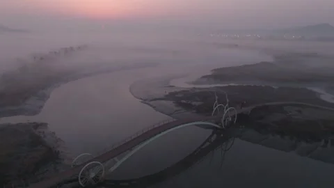 Low Aerial Flight Through Bicycle-Shaped Bridge Toward Rising Sun Stock Footage 344523203