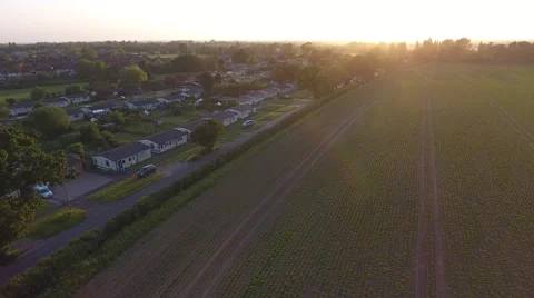 Low aerial flyover approaching suburb adjacent UK countryside at sunset Stock Footage 63840285